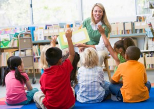 Kindergarten teacher reading to children in library
