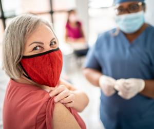 women wearing mask with bandage on arm after vaccine