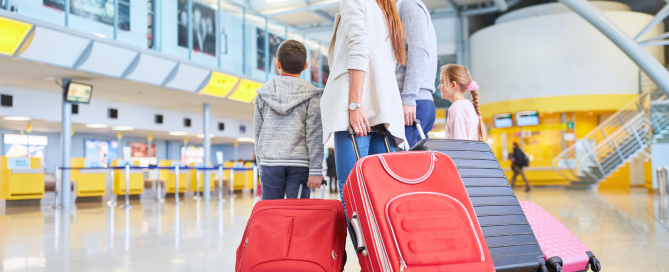image of couple walking through airport pulling their suitcases behind them.