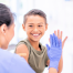 image of young boy at a doctors office and giving a high five to his provider. He is smiling big and we see the back of the provider and her hand in a medical glove.