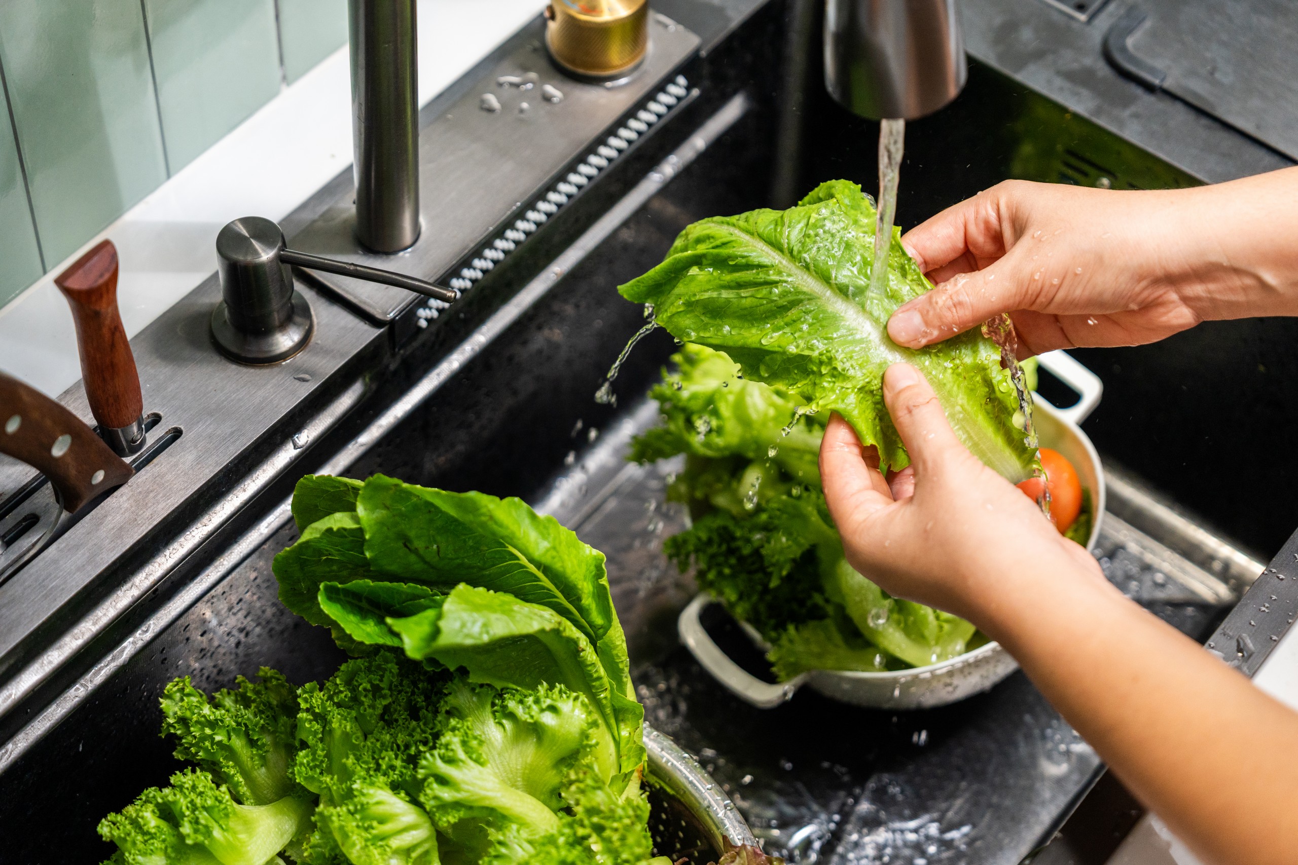 washing a leaf of lettuce in the sink