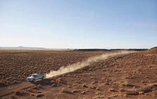 truck driving through dusty desert road